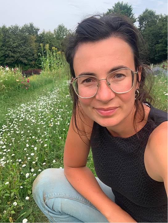 Lucette Gosselin posant devant un pré avec des fleurs à la ferme florale et apicole